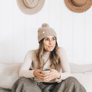 Woman wearing Will & Bear Soft Wool Beanie – Tasman Fawn – cozy indoor moment, made for winter comfort and warmth.
