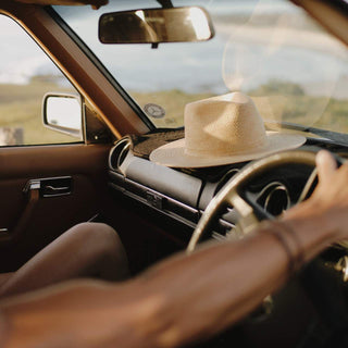 Will & Bear Wide Brim Straw Hat – Sawyer Sand – resting on dashboard, perfect for road trips and sun-soaked escapes.