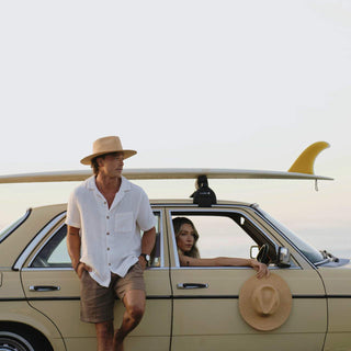 Will & Bear Wide Brim Straw Hat – Sawyer Sand – lifestyle image with hat hanging on car door, ideal for outdoor travel.