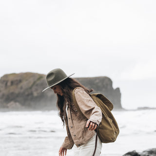 Woman Wearing Will & Bear Woodley Moss Felt Gardening Hat Walking Along Beach – Travel-Ready Wool Hat