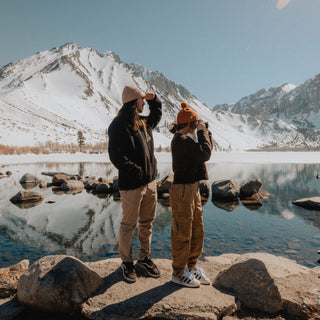 Man and woman wearing a beanie, taking photos at Convict Lake