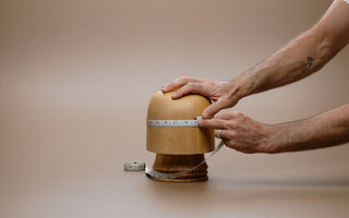 Hands taking a head measurement in studio with hat measuring tape