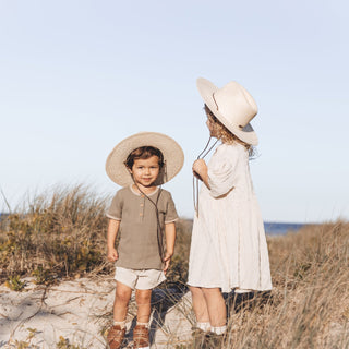 boy and girl wearing matching sun hats at the beach enjoying the sun