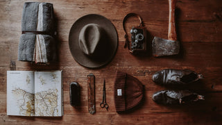 Vintage all season travel essentials including a wool hat by Will & Bear on a wooden surface.