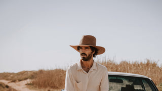 Man sitting on the front of a vinatge car in his mens straw hat by Will & Bear