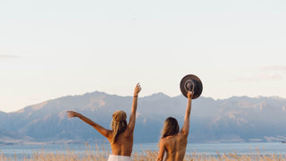 Two women celebrating with hat in the air at festival