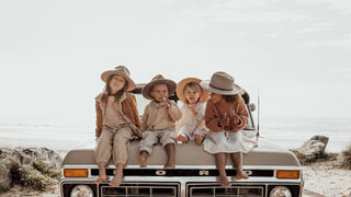 Kids and toddlers wearing wide brim sun hats by Will & Bear sitting on a vintage car 