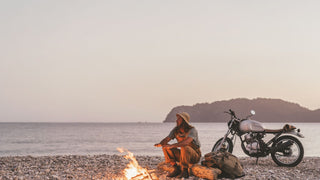 A man at a campfire on the beach wearing a bucket hat by Will & Bear