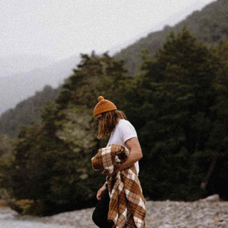 Man wearing Australian wool beanie holding a picnic rug 