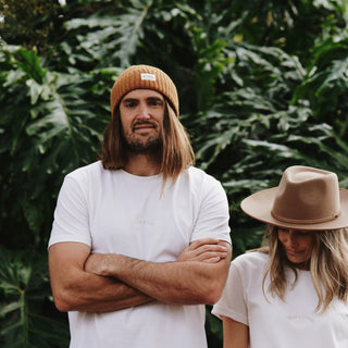 Man and woman wearing organic and recycled cotton tees with a wool beanie and hat