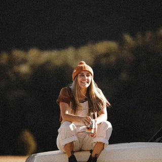 woman wearing orange beanie sitting on top of the car