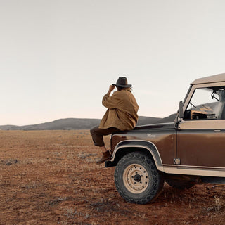 Couple sitting on 4WD wearing Anderson Olive hats in rugged landscape