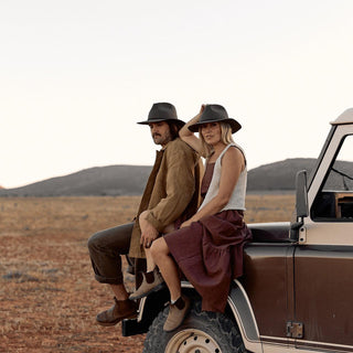 Couple sitting on vehicle hood wearing matching Anderson Olive hats