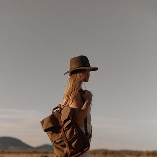 Side profile of woman with long hair wearing Anderson Olive hat outdoors