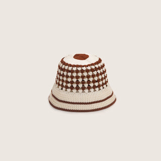 Knitted bucket hat with brown and white pattern on a light beige background