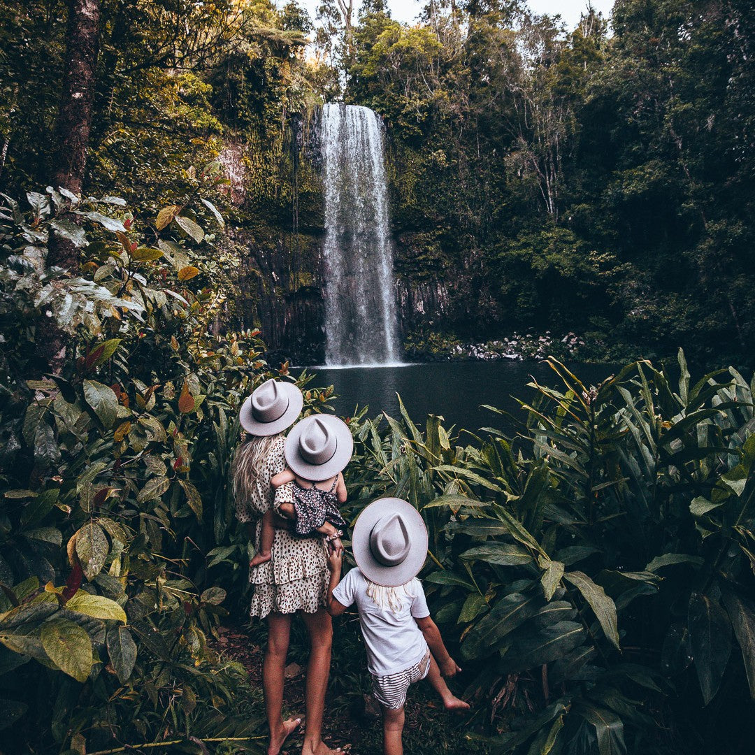 Mum with two kids in front of a waterfall wearing hats