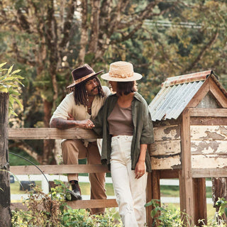 Man and woman hanging by a fence wearing wide-brim wool hats