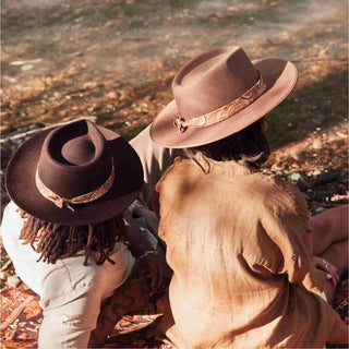 Man and woman sitting on a picnic blanket wearing wide-brim wool hats