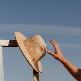 Man reaching for rustic straw beach hat Jude Sand by Will & Bear