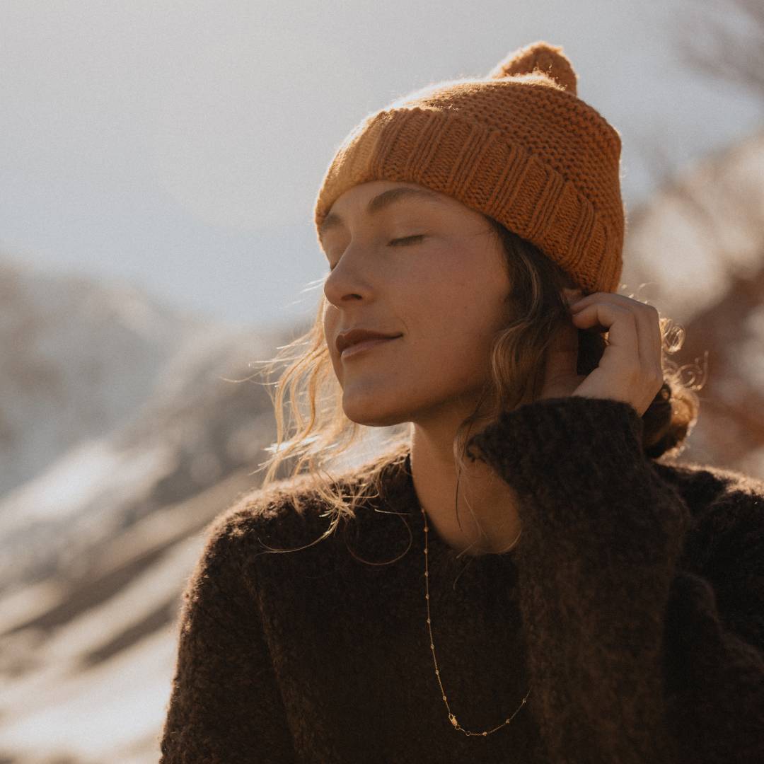 Woman with long, curly hair wearing a beanie outdoors