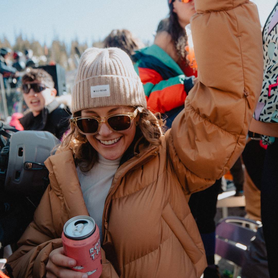 Woman with long, curly hair wearing a beanie at a ski resort party