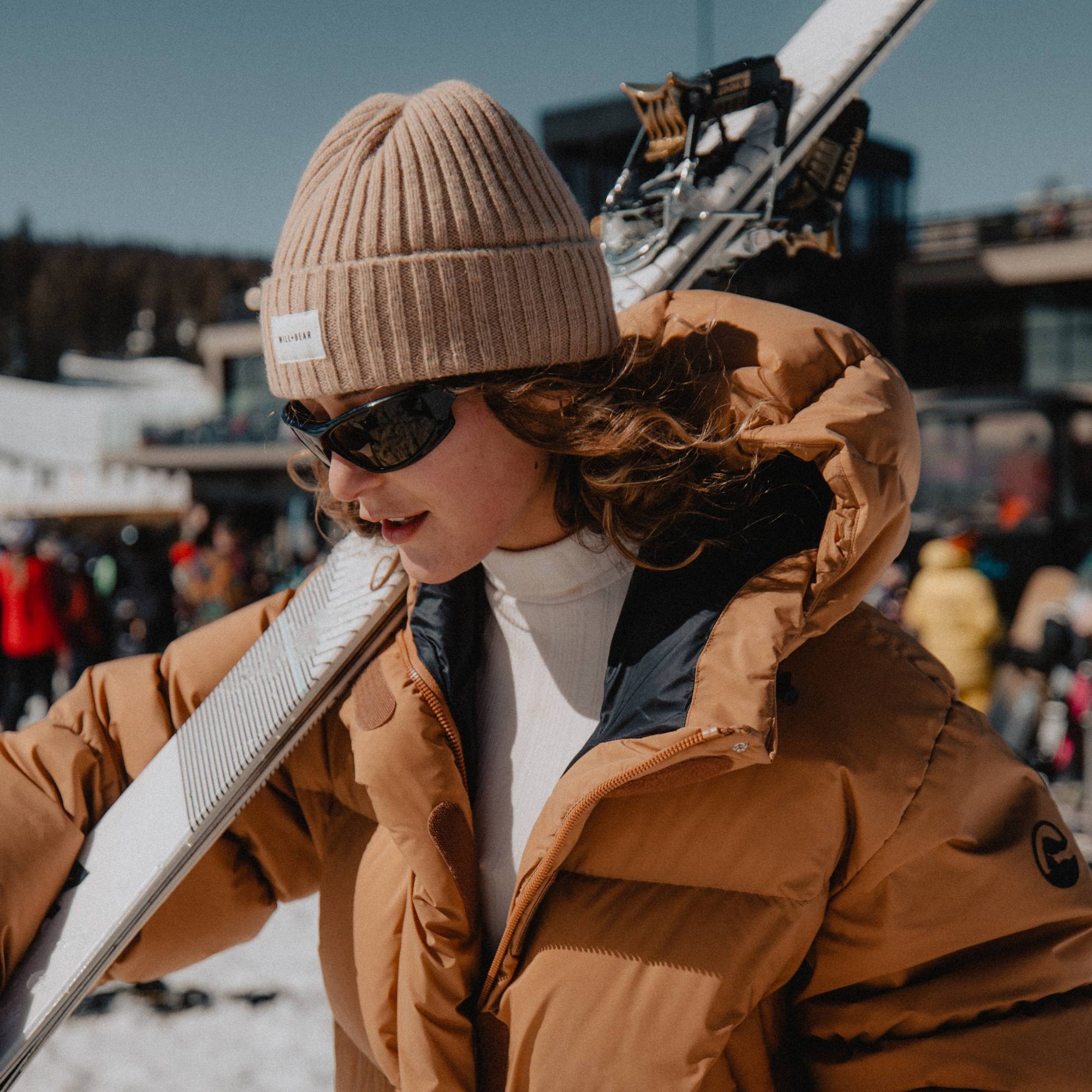 Woman with long, curly hair wearing beanie at ski slopes