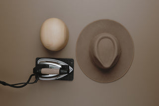 Flat lay of a iron for steam, a hat black and a brown Will & bear hat