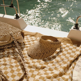 Woman in white shirt wearing Ari Sand visor hat by the water