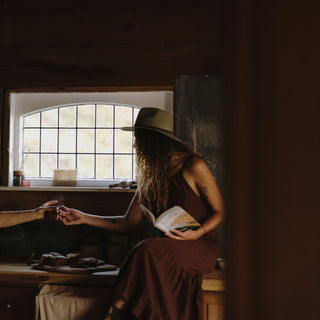 Woman wearing wide-brim floppy hat being passed a cup of team