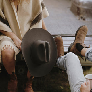 Back view of a seated person wearing the Will & Bear Buck Smoke black felt cowboy hat with natural light catching the crown.