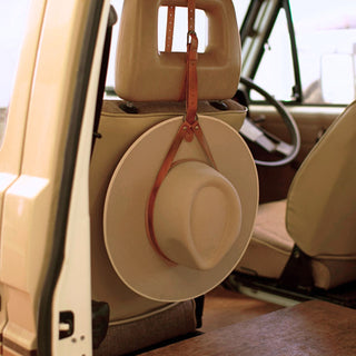 Wide brim hat hanging from leather holder on car seat