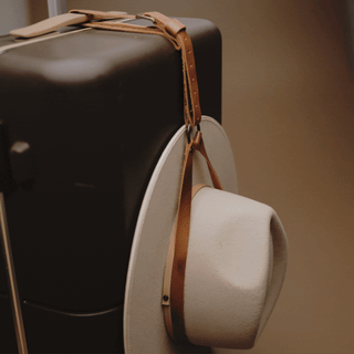 Leather hat holder carrying three wide brim hats in motion