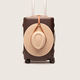 Leather hat holder clipped to suitcase handle in studio