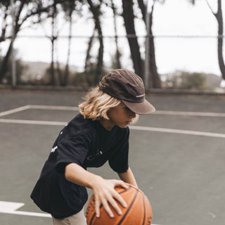 Young boy playing basketball while wearing the Little Archie Walnut kids hat