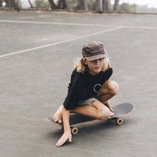 Boy Riding skateboard wearing Little Archie Walnut kids hat