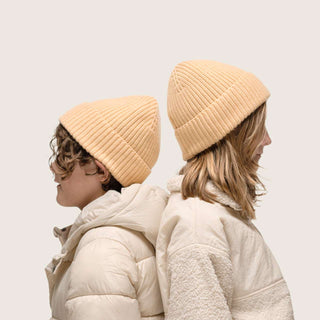 Boy and girl standing back to back wearing Little Bambi Apricot orange knit beanie