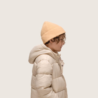 Boy wearing Little Bambi Apricot orange knit beanie standing side on to camera