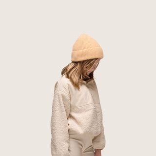 Girl looking to the ground wearing Little Bambi Apricot orange knit beanie