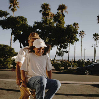 Dad and son riding a bike wearing the Riley Bone Baseball cap