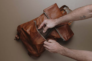 Folded brown felt hat being placed in a backpack