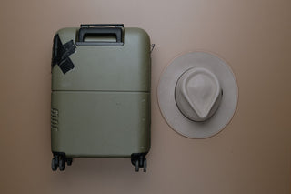 A carry on suitcase and a hat to show how wide the suitcase is