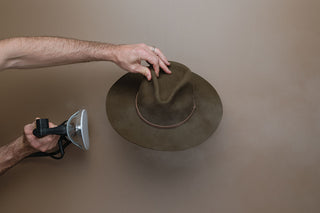 Applying steam to hat to loosen wool felt