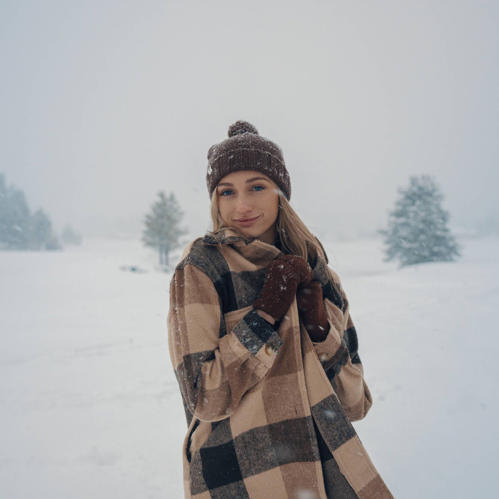 woman with long hair standing in the snow wearing a beanie