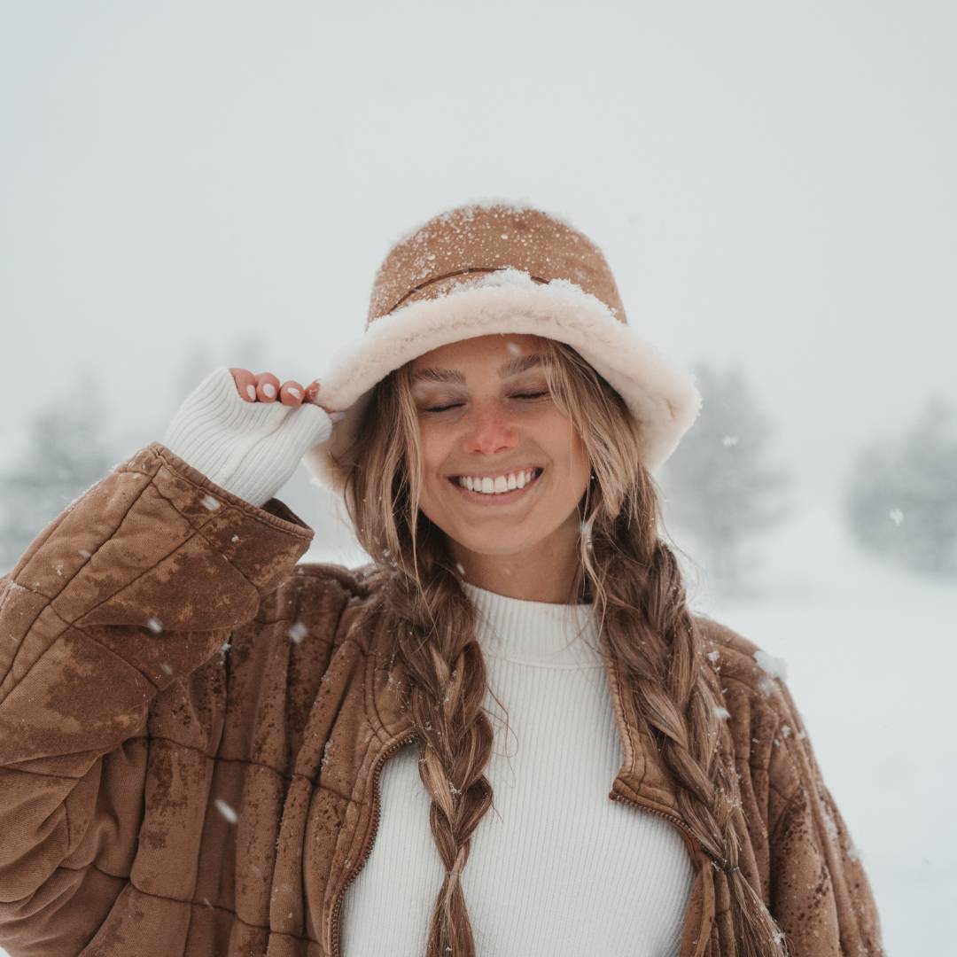 Woman with long hair wearing a sherpa bucket, standing in the snow