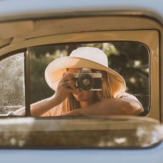 Woman taking a photo wearing a white cream bucket hat