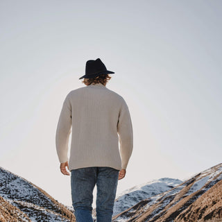 Back view of man wearing Will & Bear Anderson Navy Soft Felt Fedora while hiking in mountain ranges