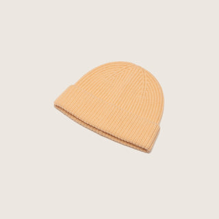 Will & Bear Bambi Apricot merino wool beanie laid flat on a neutral background, showing ribbed texture and curved shape.