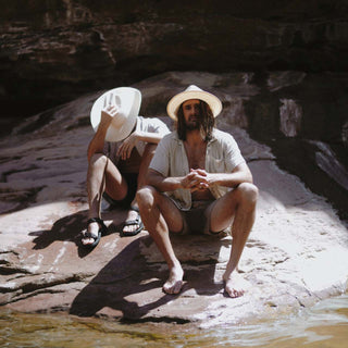Couple sitting on rocks near water, both wearing the Will & Bear Calloway Bone white straw felt fedora.