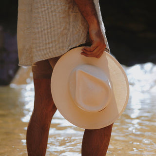 Close-up of Will & Bear Calloway Bone white straw felt fedora being held by the brim in natural light.