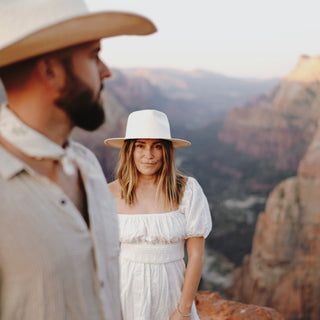 Woman wearing the Will & Bear Calloway Bone white straw felt fedora in the mountains beside her partner.